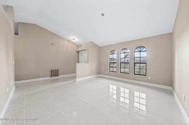 tiled empty room featuring vaulted ceiling