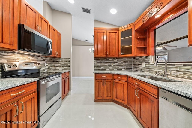 kitchen featuring light stone countertops, sink, appliances with stainless steel finishes, and vaulted ceiling