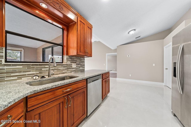 kitchen featuring light stone countertops, a textured ceiling, stainless steel appliances, lofted ceiling, and sink