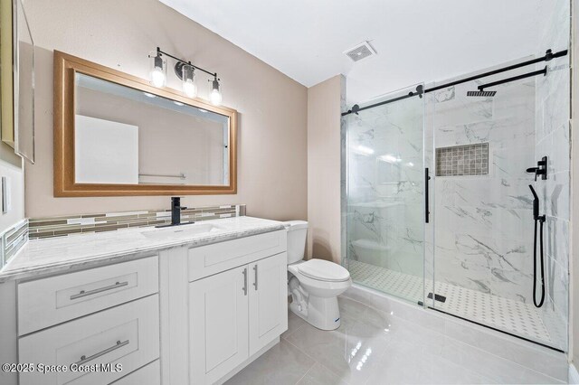 bathroom featuring toilet, vanity, tile patterned floors, and a shower with shower door