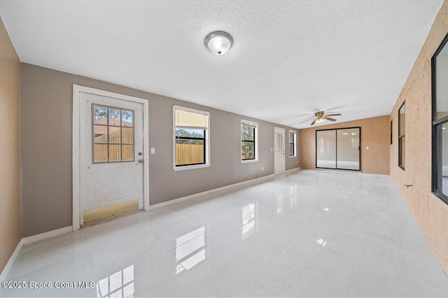 unfurnished living room with ceiling fan and a textured ceiling