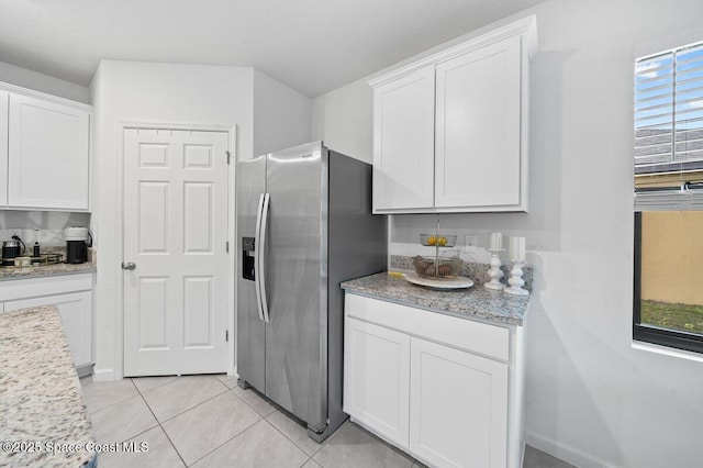 kitchen with plenty of natural light, stainless steel fridge with ice dispenser, light tile patterned floors, and white cabinetry