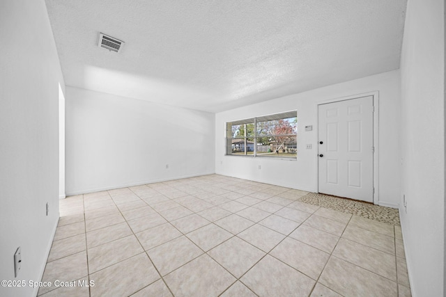 tiled empty room with a textured ceiling