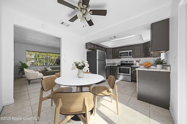 tiled dining space featuring a tray ceiling and ceiling fan