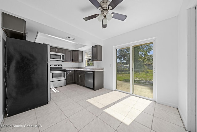 kitchen featuring sink, ceiling fan, light tile patterned flooring, dark brown cabinetry, and stainless steel appliances