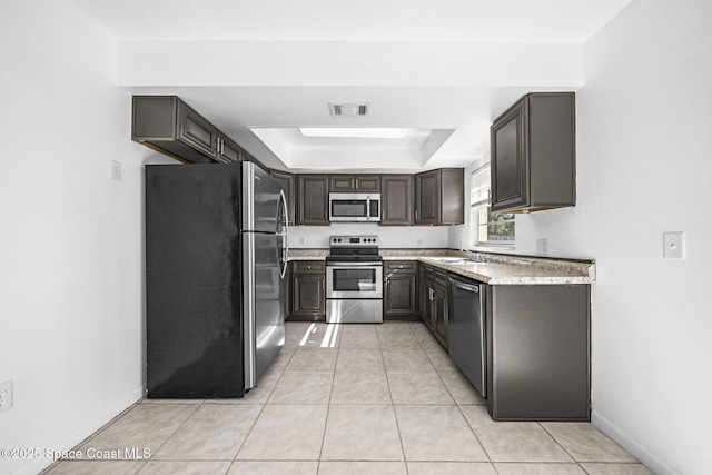 kitchen with a raised ceiling, sink, light tile patterned floors, dark brown cabinetry, and stainless steel appliances