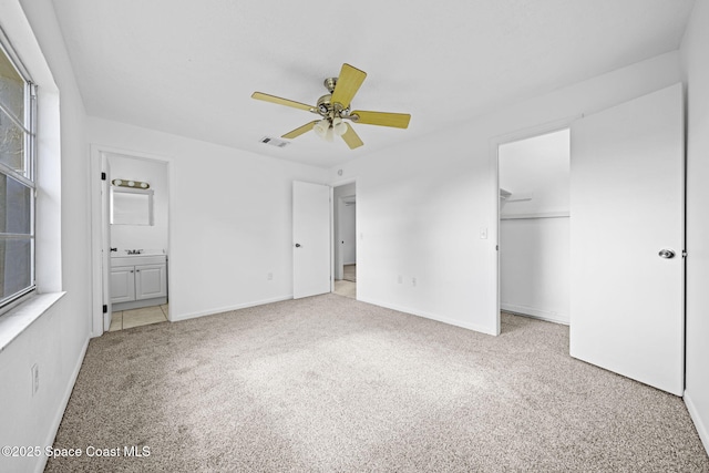 unfurnished bedroom with light carpet, a closet, ensuite bath, and ceiling fan