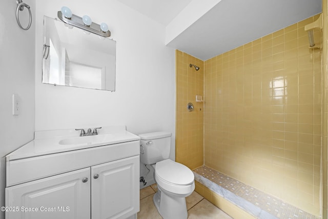 bathroom with toilet, a tile shower, vanity, and tile patterned floors