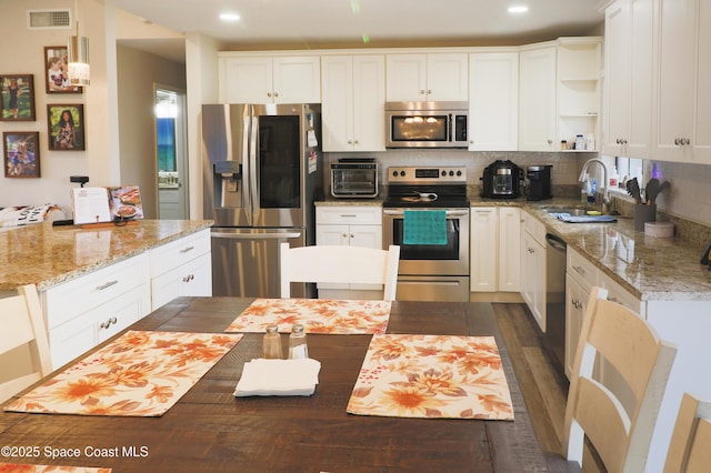 kitchen with white cabinets, appliances with stainless steel finishes, tasteful backsplash, and sink