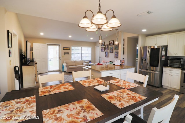 dining room with an inviting chandelier, vaulted ceiling, and dark hardwood / wood-style flooring