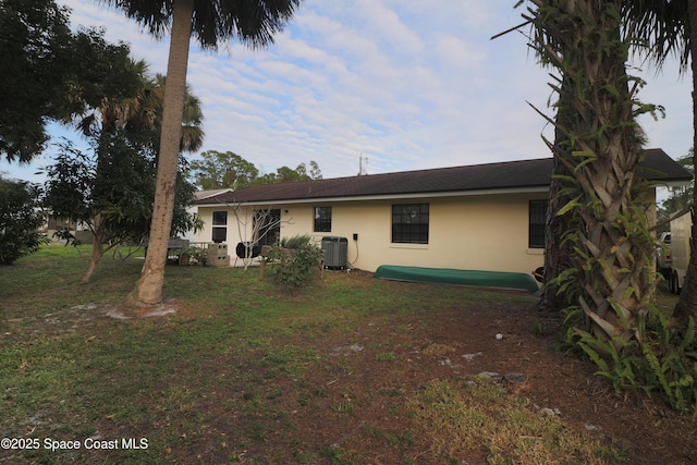 back of property with a yard and central AC