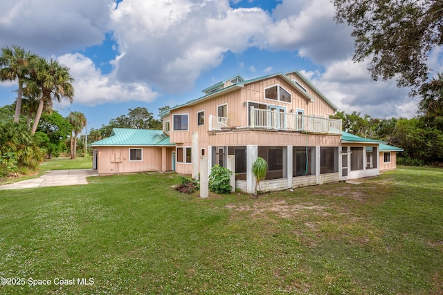 back of property featuring a balcony, a sunroom, and a lawn