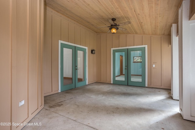 spare room featuring ceiling fan, french doors, wooden ceiling, and wood walls