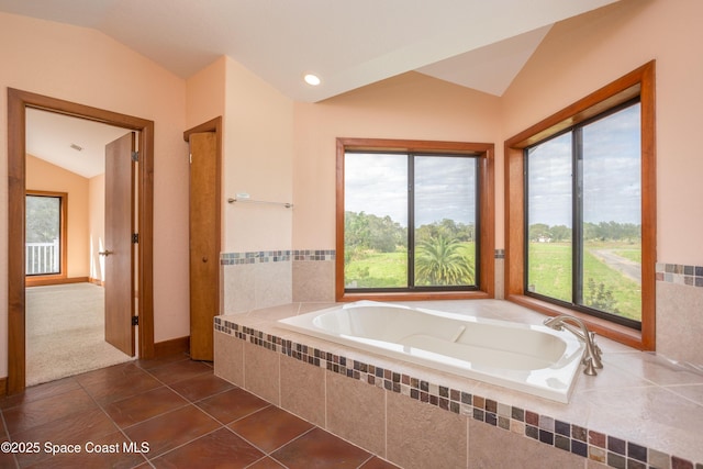 bathroom with tiled tub, tile patterned floors, a healthy amount of sunlight, and vaulted ceiling