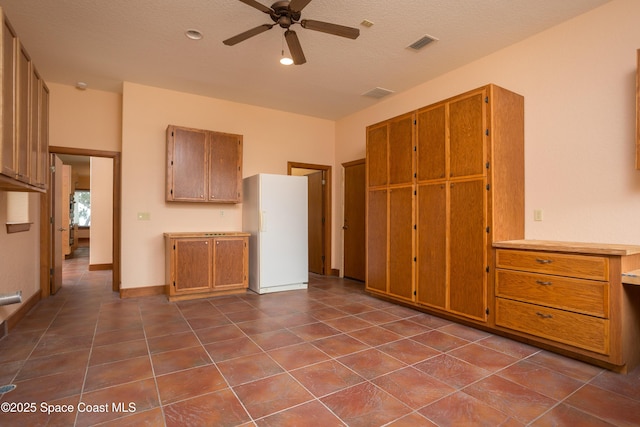 kitchen featuring white refrigerator, tile patterned flooring, a textured ceiling, and ceiling fan