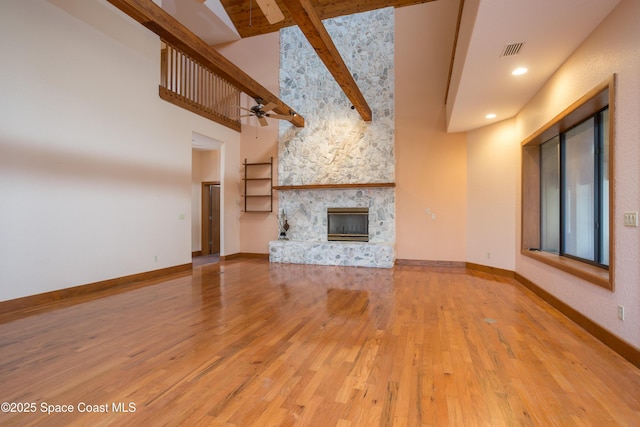 unfurnished living room with high vaulted ceiling, beam ceiling, a fireplace, ceiling fan, and wood-type flooring