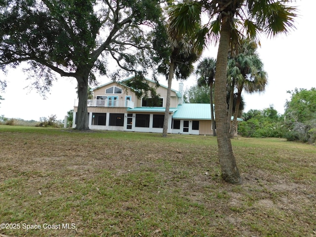 rear view of house with a balcony and a lawn