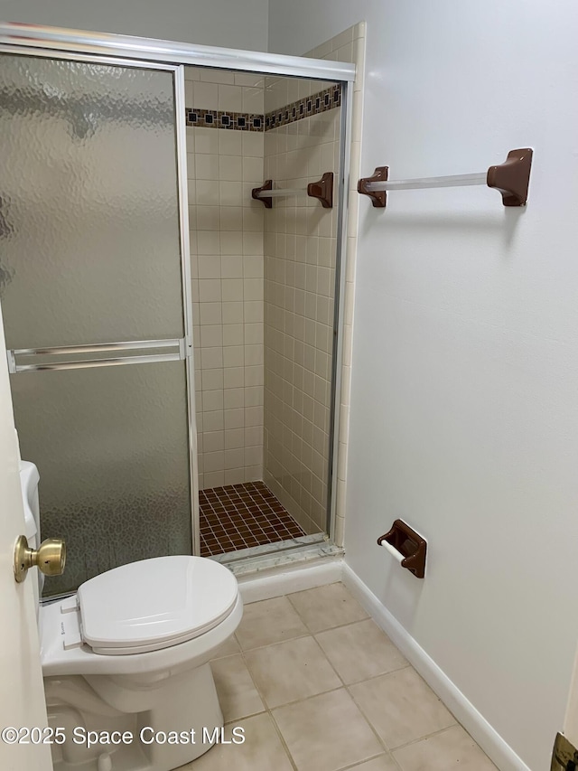 bathroom with tile patterned flooring, toilet, and a shower with shower door