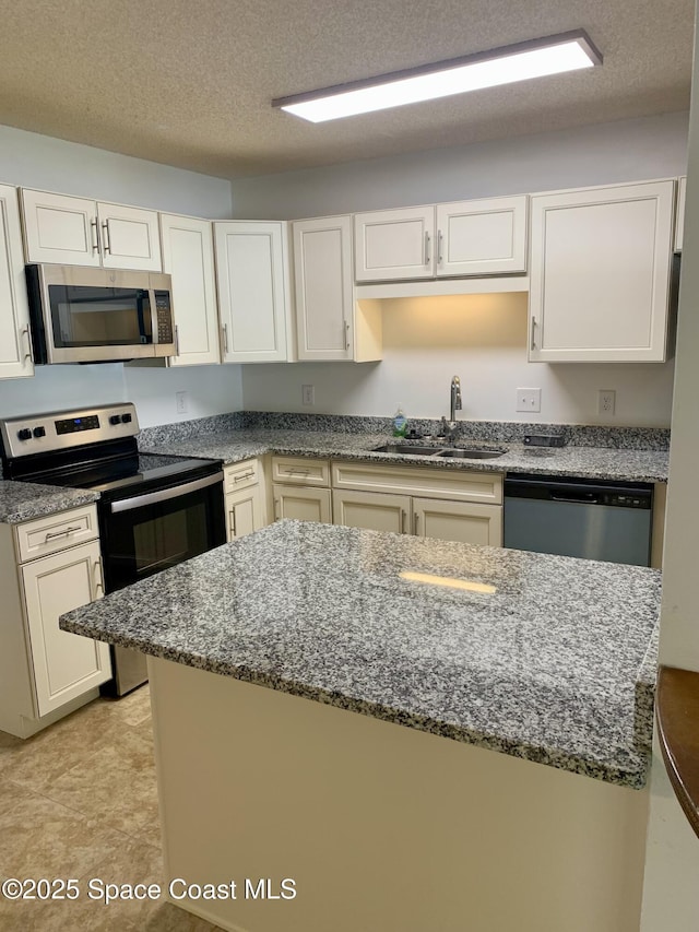 kitchen featuring white cabinetry, sink, a textured ceiling, and appliances with stainless steel finishes