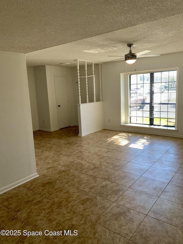 tiled empty room featuring ceiling fan and a textured ceiling