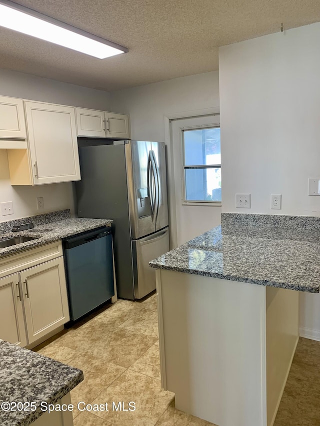 kitchen with stone countertops, white cabinets, stainless steel appliances, and a textured ceiling