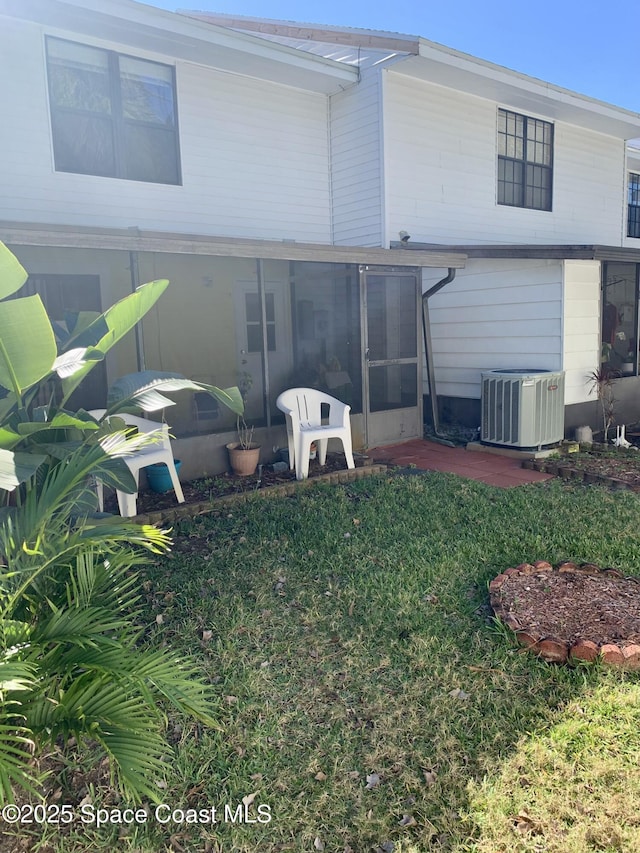 back of house featuring a sunroom, central air condition unit, and a lawn