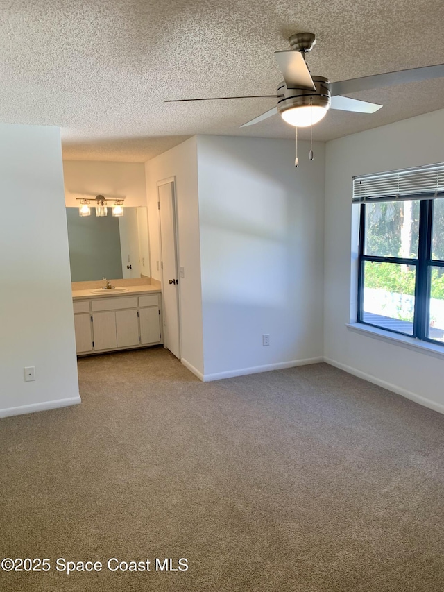 unfurnished bedroom with connected bathroom, ceiling fan, sink, a textured ceiling, and light carpet