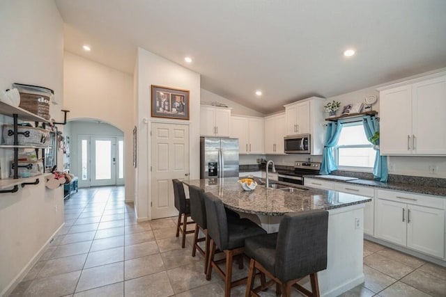 kitchen with white cabinets, appliances with stainless steel finishes, a center island with sink, and lofted ceiling