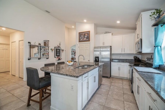 kitchen with appliances with stainless steel finishes, a kitchen island with sink, sink, white cabinets, and lofted ceiling