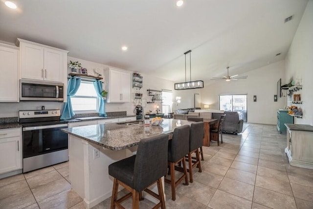 kitchen featuring white cabinets, stainless steel appliances, ceiling fan, and a center island with sink