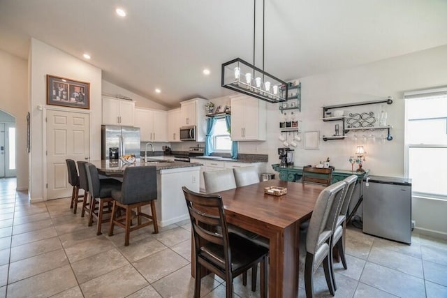 dining room with light tile patterned floors, sink, and vaulted ceiling