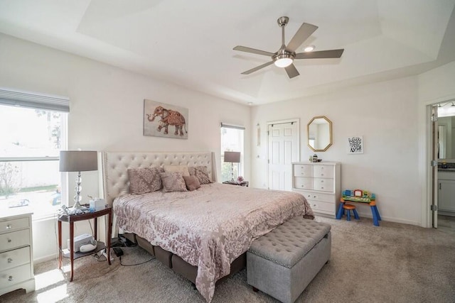 bedroom with a raised ceiling, ceiling fan, and light colored carpet