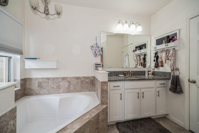 bathroom featuring vanity, a chandelier, and a relaxing tiled tub