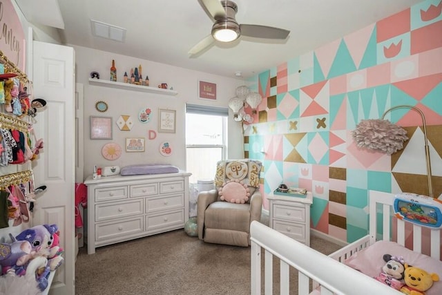 carpeted bedroom with ceiling fan and a nursery area