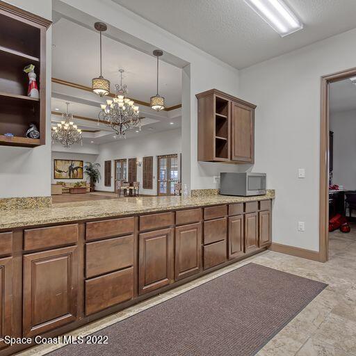 kitchen with a textured ceiling, light stone counters, hanging light fixtures, and a chandelier