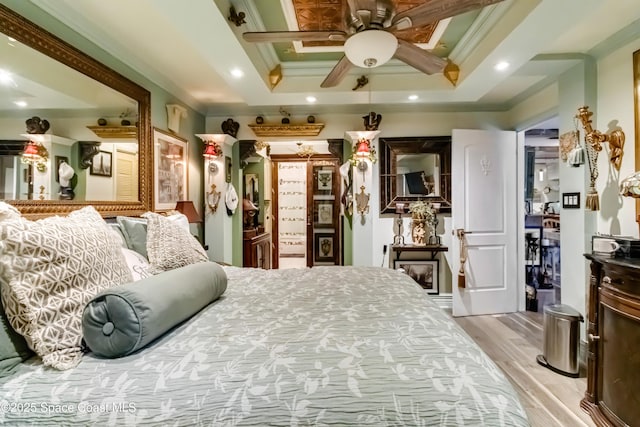 bedroom with a raised ceiling, ceiling fan, ornamental molding, and light hardwood / wood-style flooring