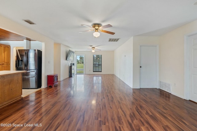 unfurnished living room featuring dark wood-type flooring and ceiling fan