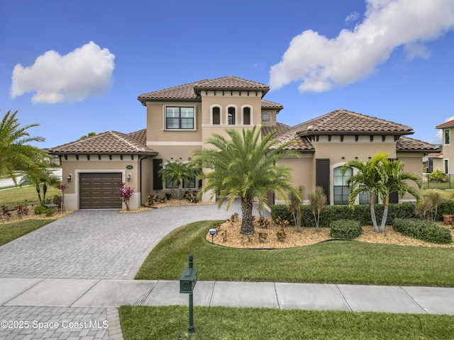 mediterranean / spanish home featuring a garage and a front yard