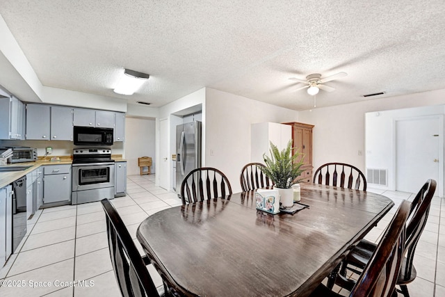 dining space featuring sink, ceiling fan, light tile patterned floors, and a textured ceiling