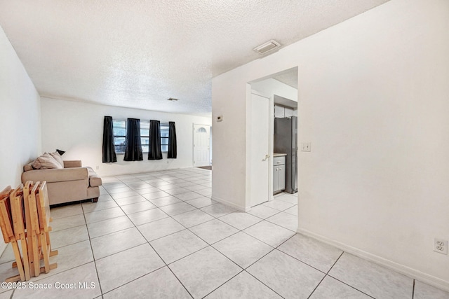 unfurnished living room featuring a textured ceiling and light tile patterned flooring