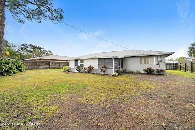 rear view of house featuring a sunroom and a lawn