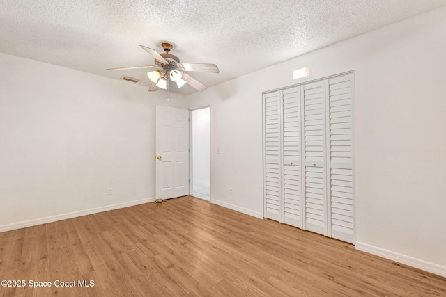 unfurnished bedroom with light wood-type flooring, a textured ceiling, a closet, and ceiling fan