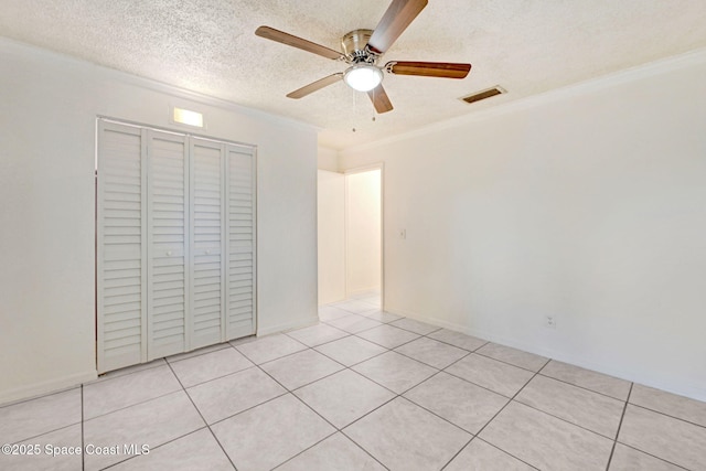 unfurnished bedroom featuring a closet, ceiling fan, light tile patterned floors, and a textured ceiling