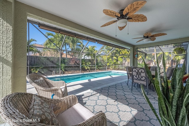 view of pool featuring glass enclosure, ceiling fan, and a patio