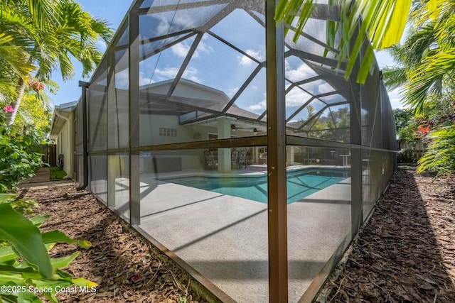 view of pool with glass enclosure and ceiling fan