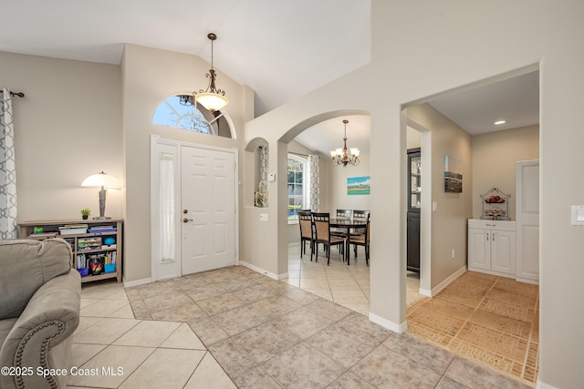 tiled foyer entrance featuring a chandelier and vaulted ceiling