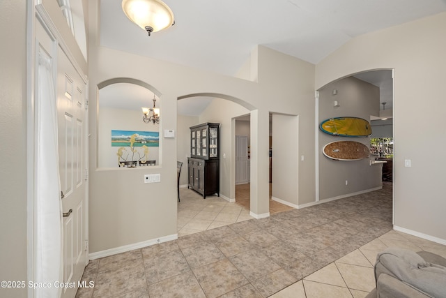 corridor featuring a notable chandelier, light tile patterned flooring, and lofted ceiling