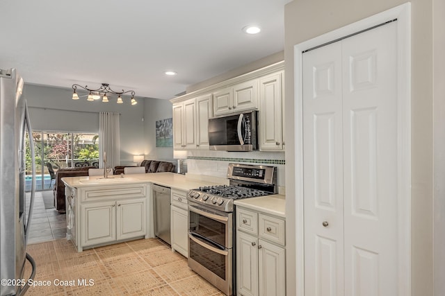 kitchen with sink, decorative backsplash, light tile patterned floors, kitchen peninsula, and stainless steel appliances