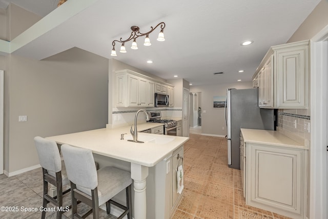 kitchen featuring a kitchen breakfast bar, sink, appliances with stainless steel finishes, tasteful backsplash, and kitchen peninsula