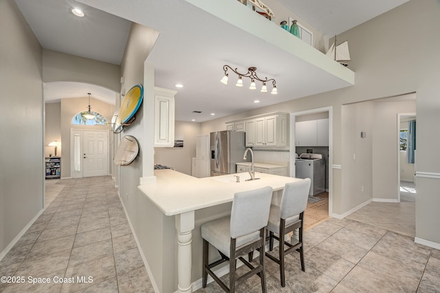 kitchen featuring kitchen peninsula, light tile patterned floors, white cabinetry, a kitchen bar, and stainless steel fridge with ice dispenser